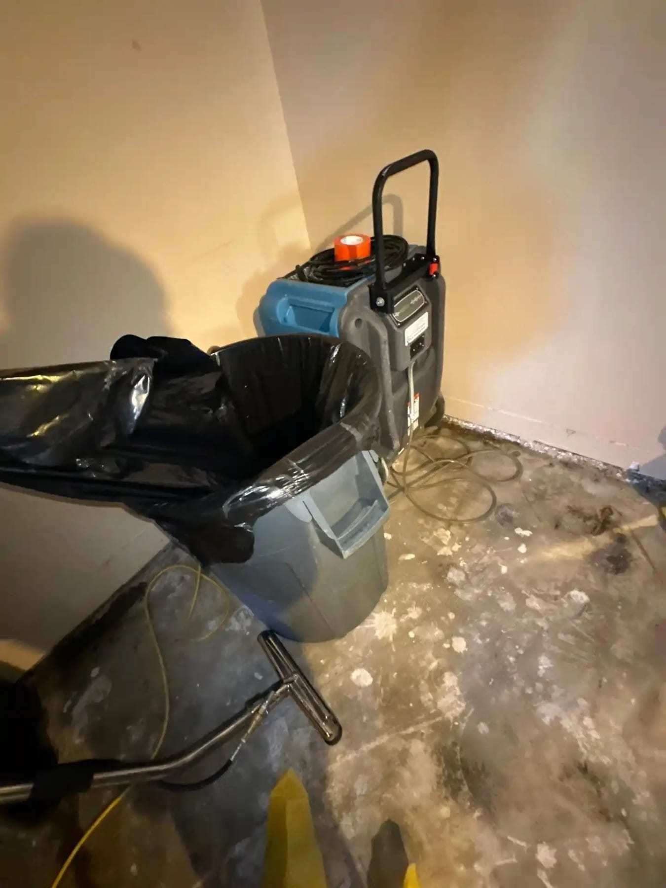 Air scrubber and a trash can on a wet basement floor
